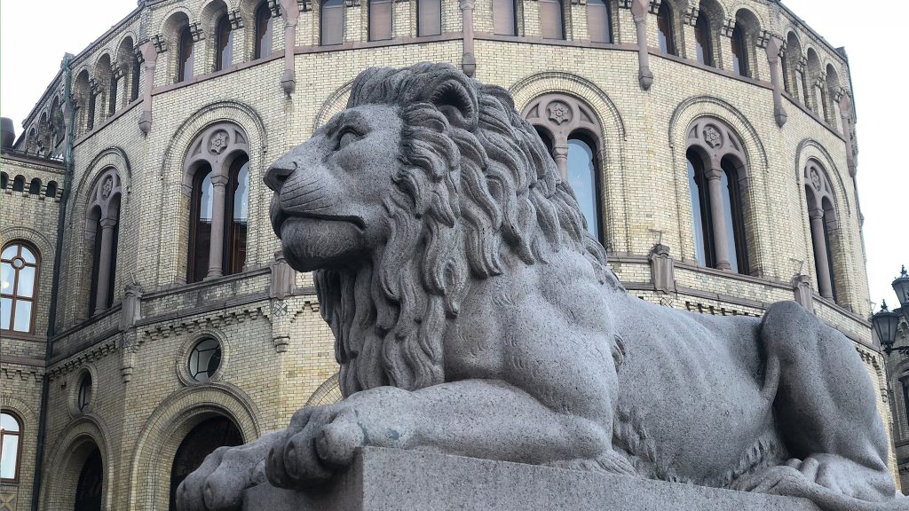 Statue av løve på Løvebakken med Stortinget i bakgrunnen